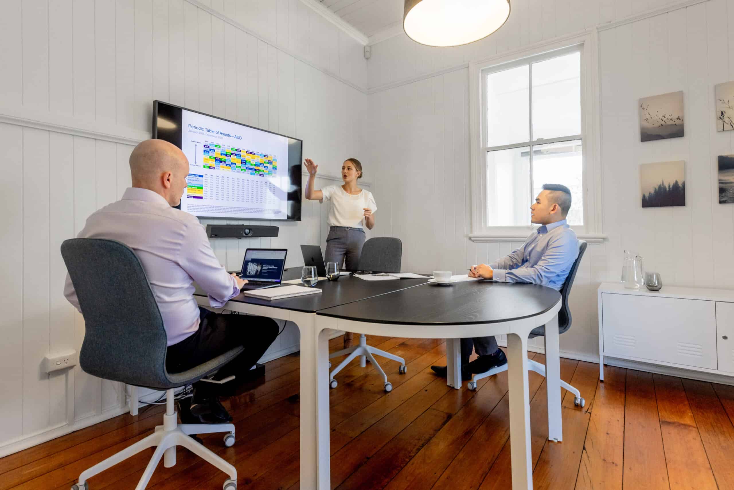 Three financial advisors gathered around a screen to discuss financial aspect of business in an office.